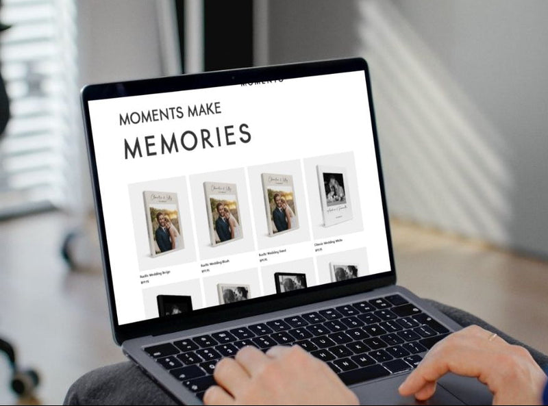 Person using a laptop with a screen displaying 'Moments Make Memories' on a blurred indoor background