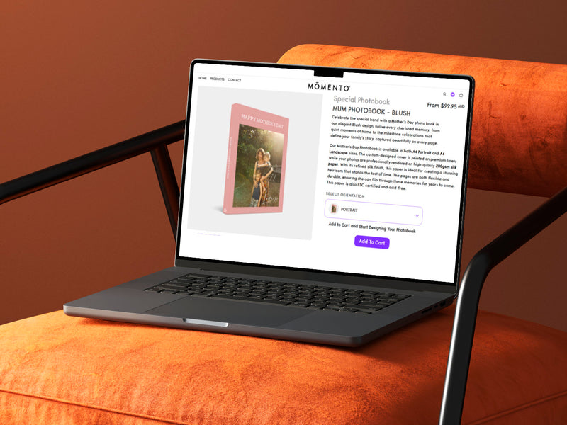 Laptop on an orange cushion displaying a photo book Momento website.